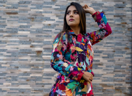 An indian female model in a coat made of colourful scraps.